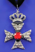 Decorative cross pendant with a red gemstone on a blue background