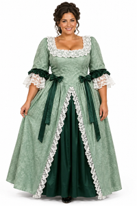 A woman modeling a historical-style green gown costume with white lace trim, dark green sashes, and three-quarter sleeves on a plain white studio background.