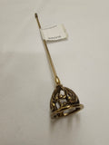 An antique brass or gold-colored hat pin with an ornate filigree bell-shaped end, shown on a white textured fabric background with a white paper tag attached.