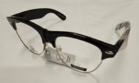 Black semi-rimless eyeglasses with clear lenses, featuring a glossy black acetate front and temples, with silver metal hinges and nose pads. The glasses are shown with their retail tags on a white textured fabric background.