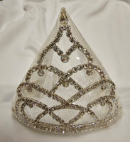 A silver tiara decorated with silver rhinestone trim and a central crystal ornament, displayed on a white fabric background.