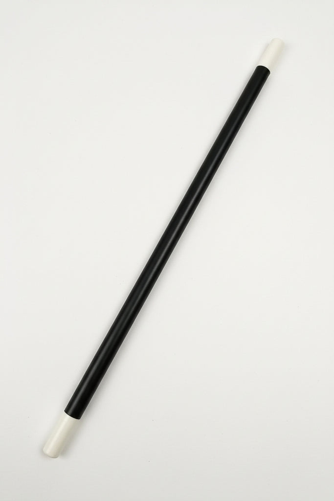 A black cylindrical rod or stick with white plastic end caps, photographed diagonally on a white textured fabric background.