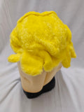 A bright yellow plush character hood displayed on a beige mannequin head with a black base, photographed against a white fabric backdrop.
