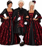 A man with 2 woman modeling a historical or period costume consisting of a black doublet jacket with red patterned trim, black breeches, white stockings, white gloves, and a white powdered wig, photographed against a plain white background.