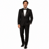 A man modeling a classic black tuxedo with satin peak lapels, a white dress shirt, a black bow tie, and black dress shoes against a plain white background.