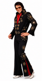 A man modeling a black Elvis Presley-style costume jumpsuit with gold embroidered starburst patterns and a red inner collar, paired with white cowboy boots and sunglasses, on a white background.