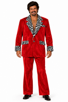A man modeling a red velvet two-piece suit with black and white zebra print lapels, pocket flaps, and cuffs, paired with black dress shoes against a white background.